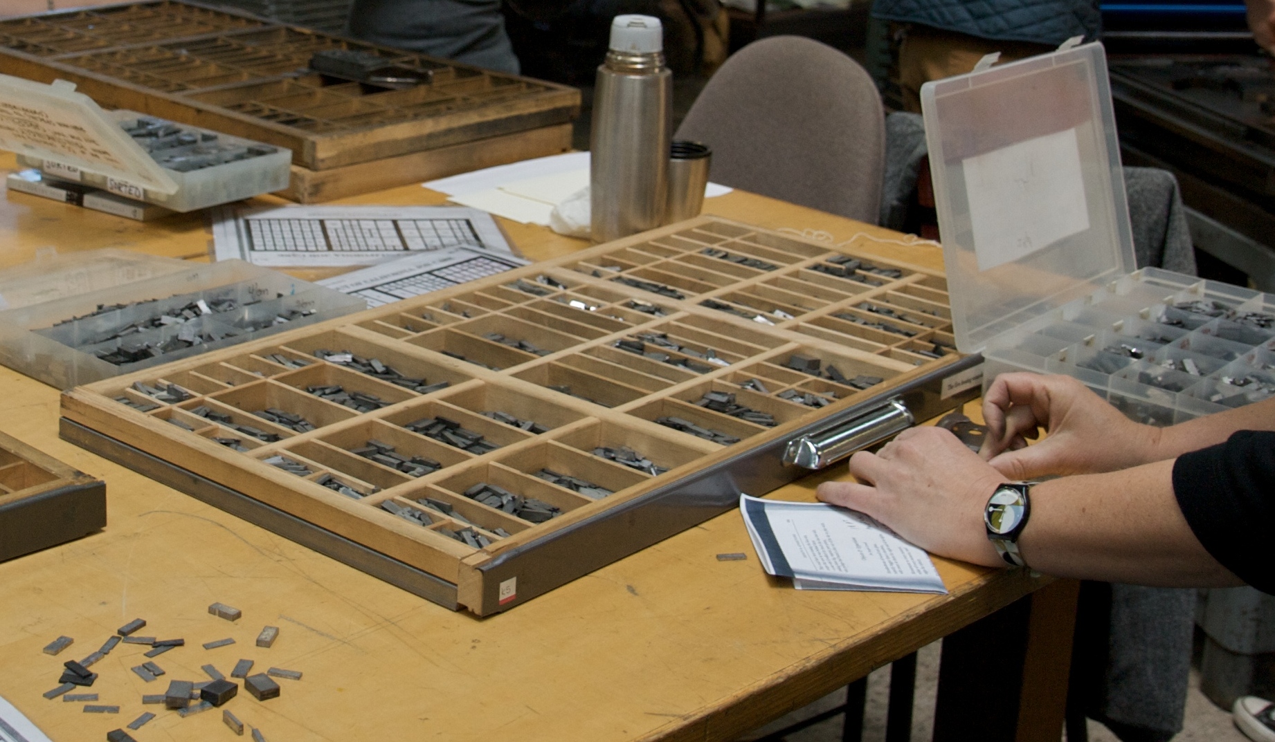 A California job case — a flat wooden tray divided into many compartments of varying sizes, each holding pieces of moveable type. The compartments are arranged hierarchically by frequency of use.